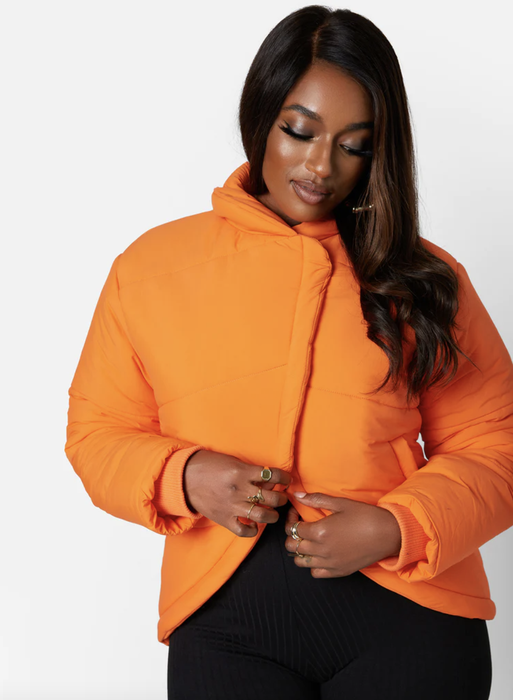 Model styling a bright orange cropped puffer jacket with a chic crossover front