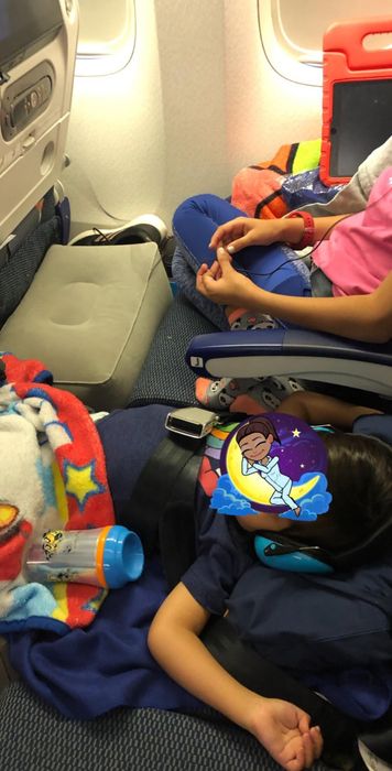 Image of two kids using the footrest while seated on a plane