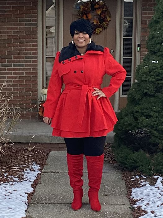 A reviewer wearing the coat in bold red