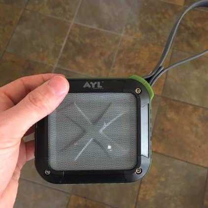 A reviewer holding the palm-sized green speaker.