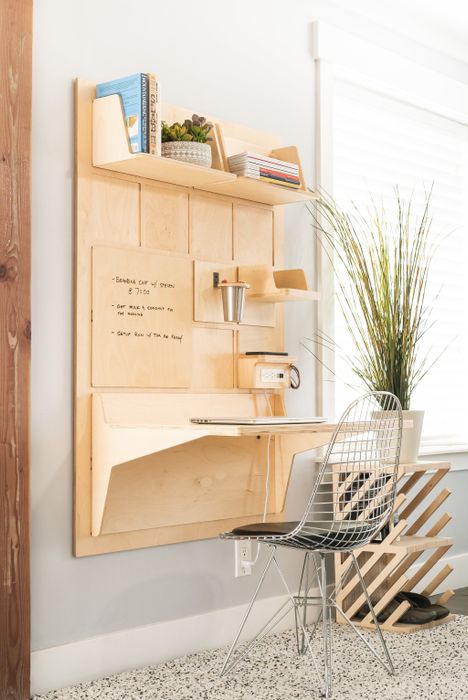 A wall-mounted natural birchwood desk with a tabletop, shelves, an outlet charging station, and a dry erase panel.