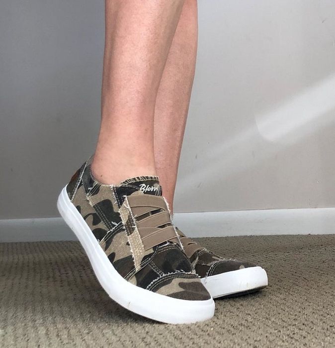 Reviewer showing off camouflage sneakers with white soles