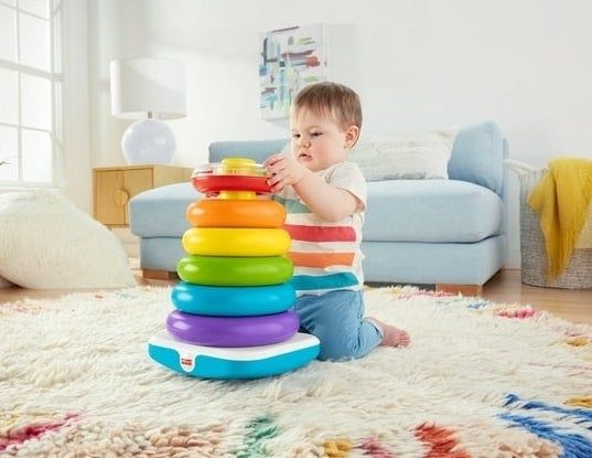 A child enjoying playtime with a colorful circle stacking toy on the floor.