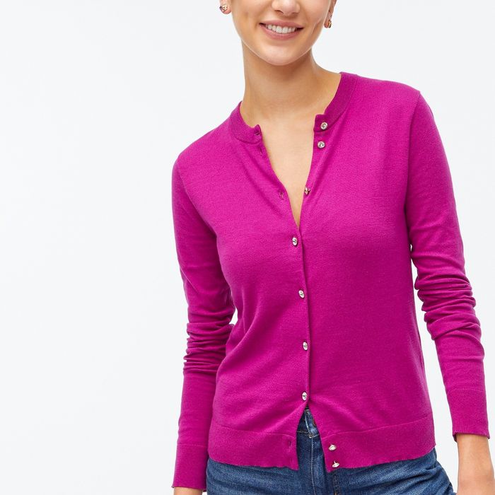 A model wearing a magenta cardigan adorned with silver and diamond-like buttons