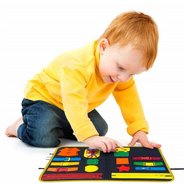 A boy playing with clips on a busy board