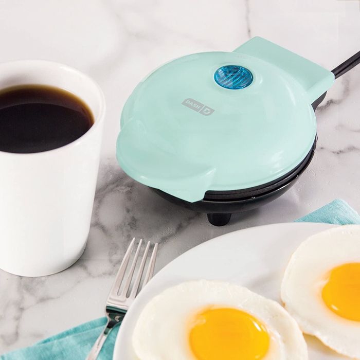 The soft blue griddle next to a coffee mug, almost the same size in diameter.