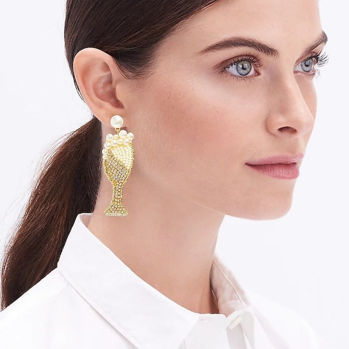 A model wearing elegant gold and pearl champagne earrings with a crisp white shirt