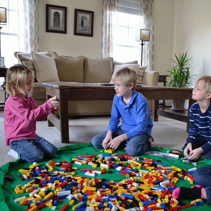 Kids enjoying playtime with toy blocks on a mat in a cozy living room atmosphere
