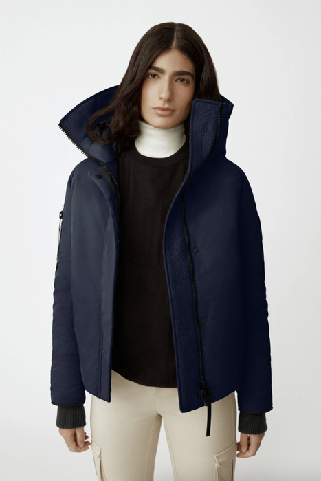Model rocking a dark blue bomber made from performance satin, featuring an oversized hood pulled up.