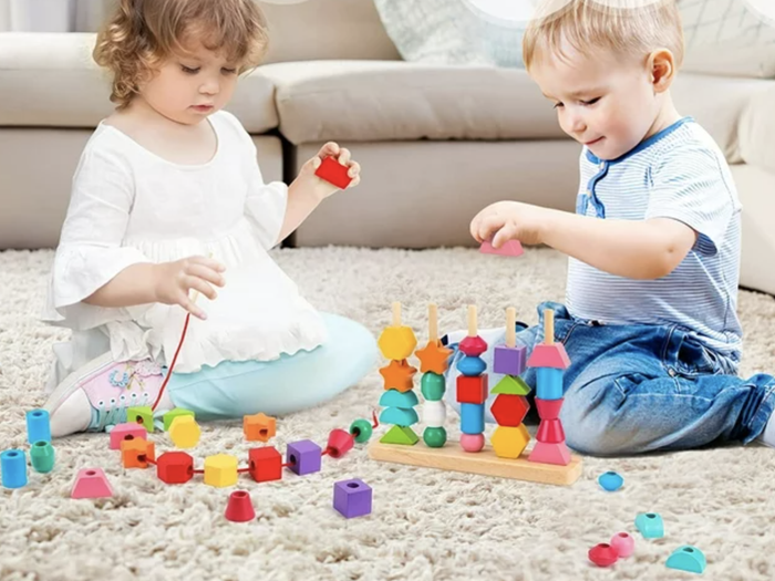 Toddlers having a blast with colorful wooden stacking beads in various shapes