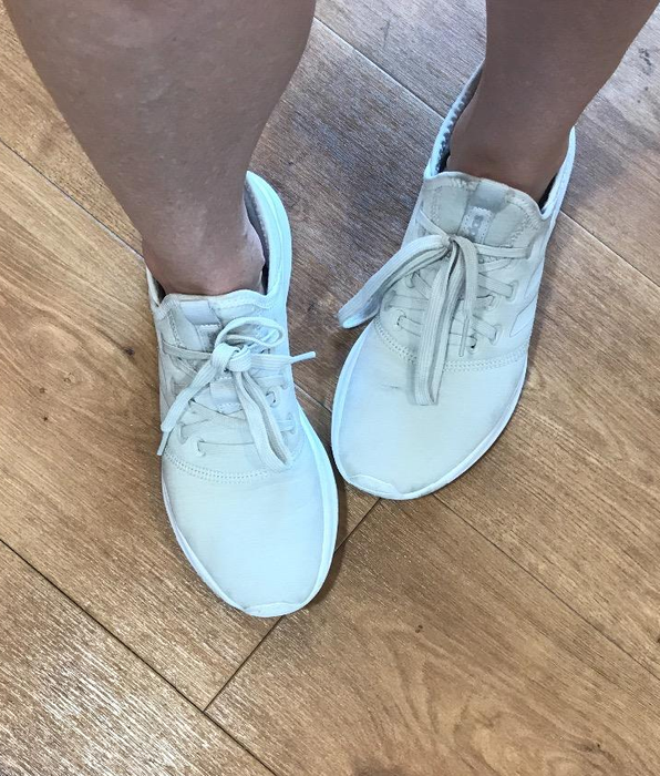 A reviewer showcasing the white version of the Adidas Cloudfoam sneakers.