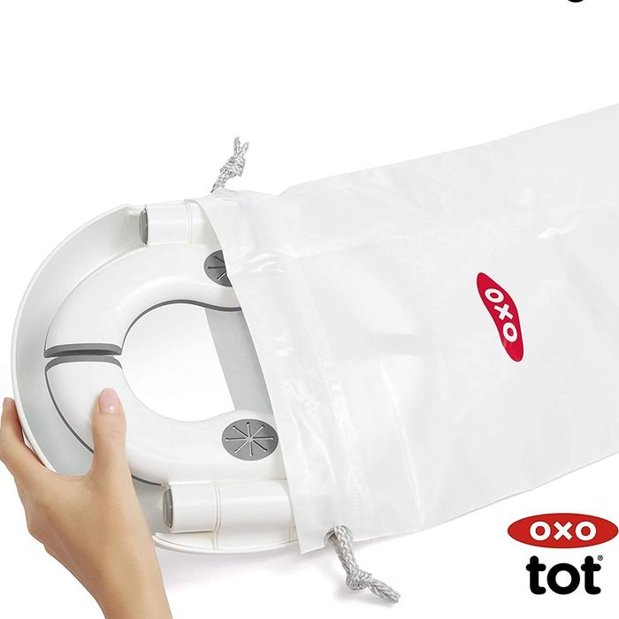 A hand holding an OXO tot product, complete with a travel bag, highlighting its portability for on-the-go shoppers.