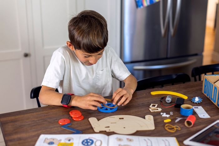 a child assembling a toy on a wooden table