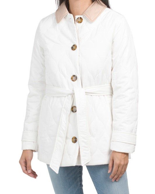 Model wearing a white quilted jacket, featuring a front tie and a tan collar.