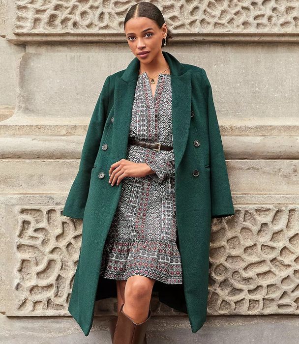 A model wearing a long, elegant green peacoat
