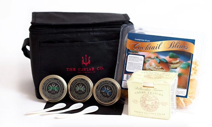 Complete caviar kit featuring three jars, blinis, crème fraîche, and a stylish carrier bag.