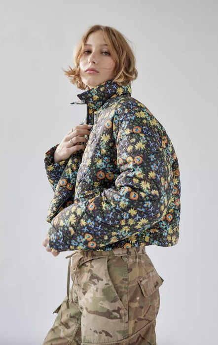 Model flaunting a quilted, cropped black puffer jacket adorned with multi-colored flowers