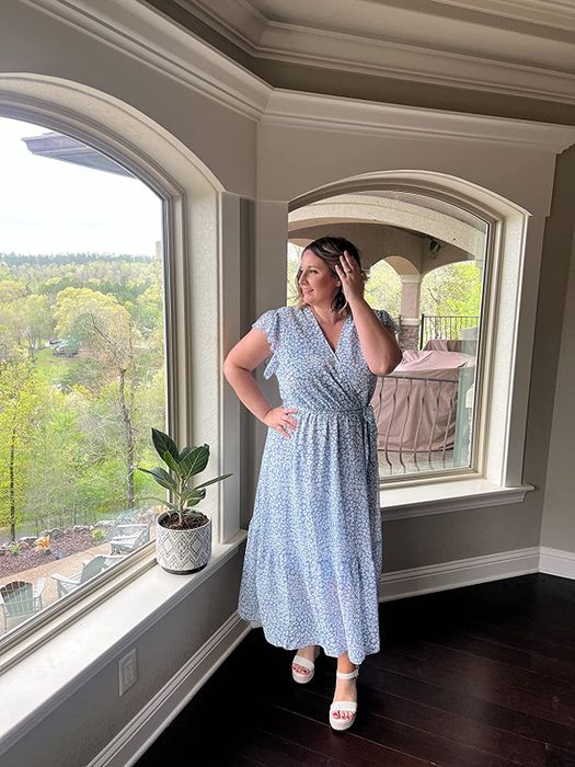 The reviewer is wearing a soft blue wrap dress.