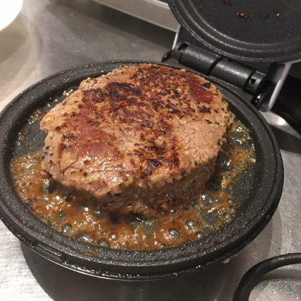 The fully cooked meat patty, sizzling and ready to go.