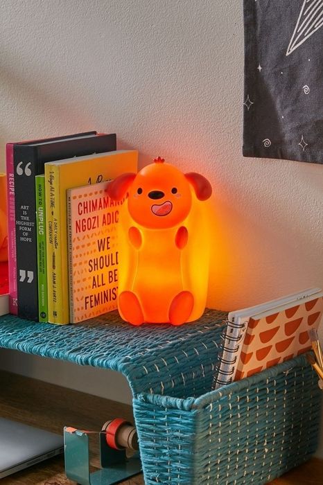 The LED light takes the shape of a hot dog with paws and a dog’s head in a bun, sitting on a bookshelf. It’s about the size of a paperback book.