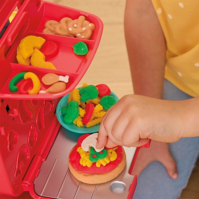 A child enjoying a toy food set, arranging pretend pizzas and snacks for playtime.
