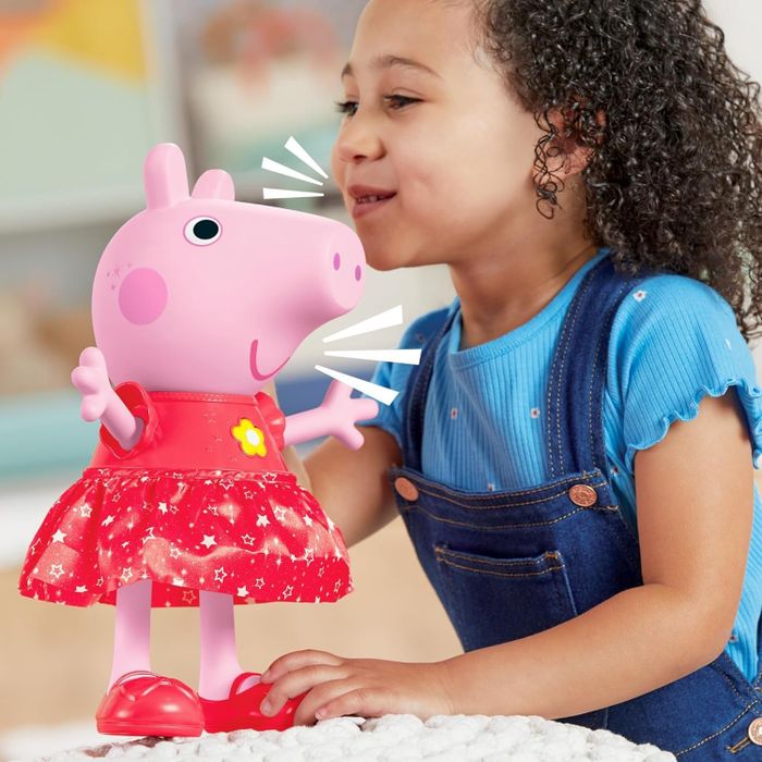 A child grinning while playing with a Peppa Pig plush toy
