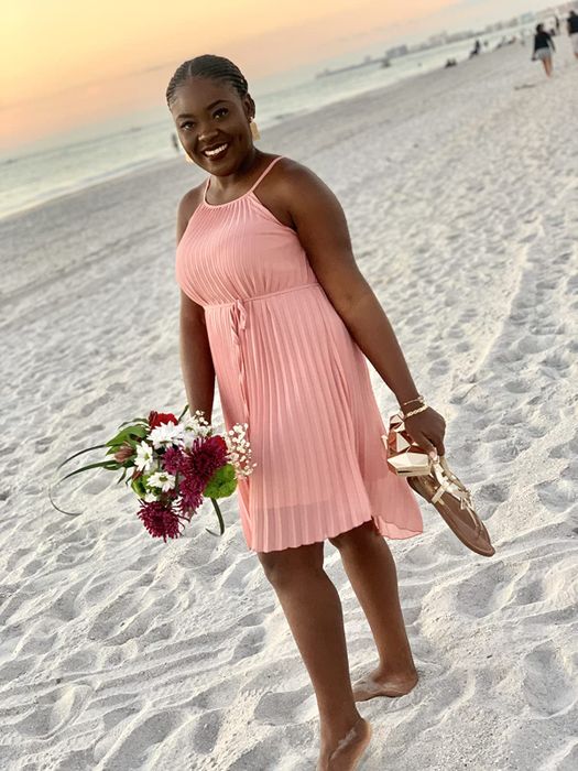 A reviewer wearing the soft pink dress to a beach wedding