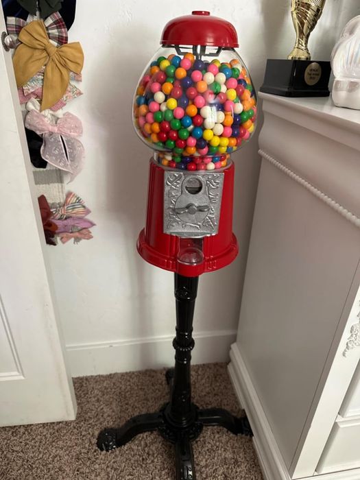 Reviewer’s red gumball machine with a stand, filled with colorful gumballs