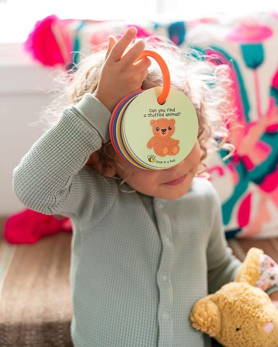 child holding ring of circular cards in front of face