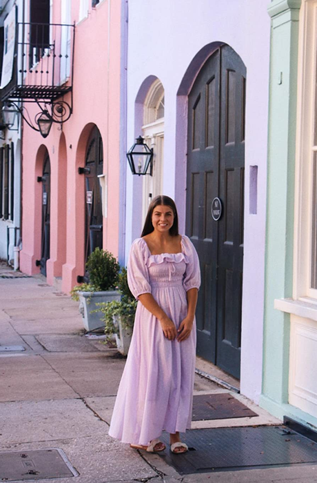 A reviewer wearing the pink dress with the sleeves gracefully resting on their shoulders