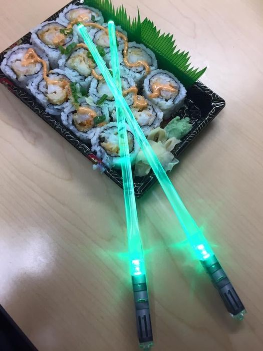 Reviewer’s glowing green chopsticks placed on top of a sushi roll.