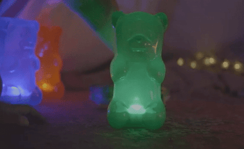 A gif of the glowing green gummy bear-shaped lamp.