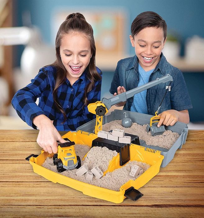 Two models playing with the kinetic sand folding sandbox playset