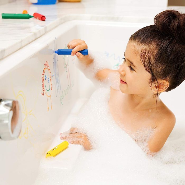 A child drawing with bath crayons in the tub