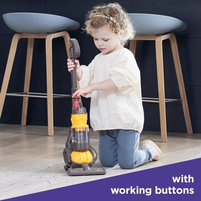 A child operating the yellow toy vacuum
