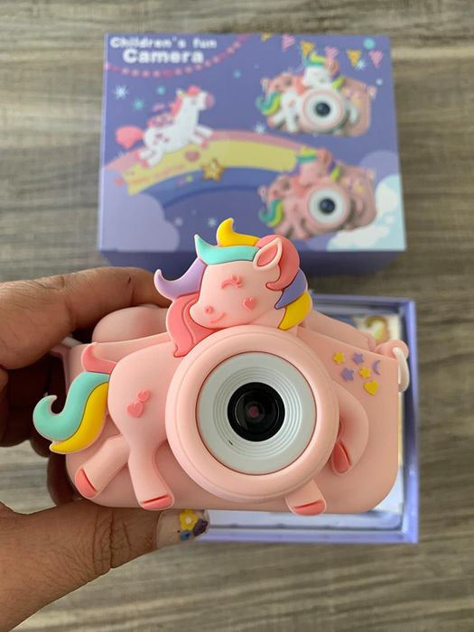 A unicorn-themed toy camera with a rainbow mane detail, and the packaging visible in the background