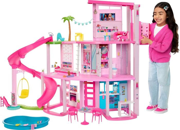 A child playing with a three-story Barbie dollhouse