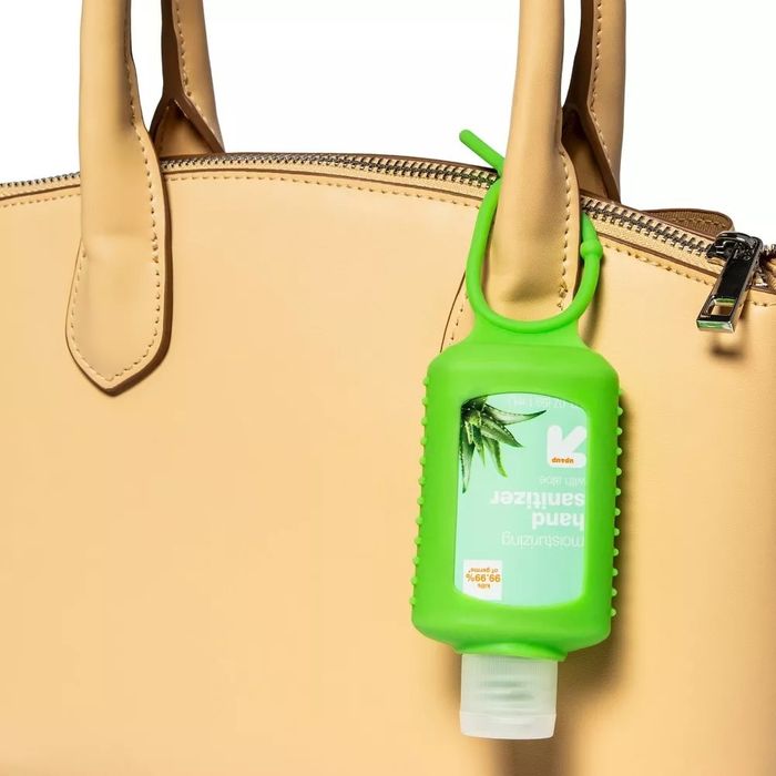 A green gel wrap holding a travel-sized hand sanitizer bottle attached to a bag
