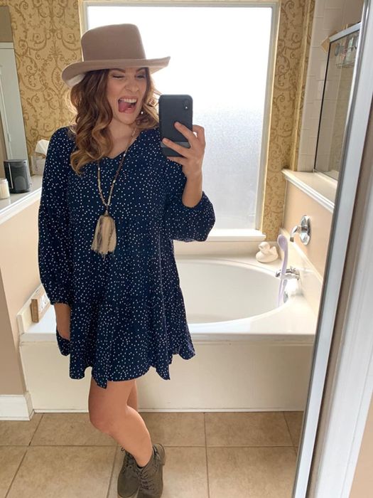 A reviewer styling the dress in a playful navy polka dot pattern