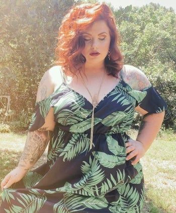 Reviewer in a black cold-shoulder dress with green tropical leaves on it