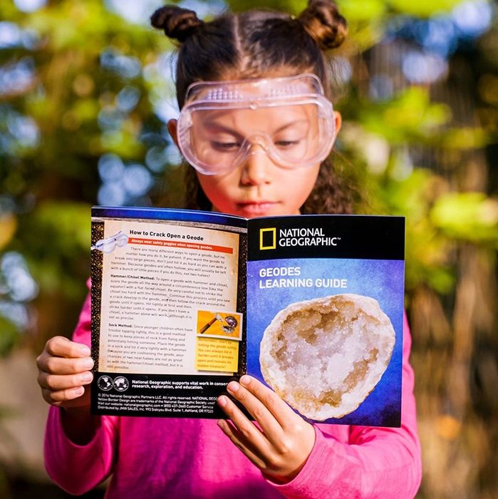 A model holding the National Geographic geode exploration book