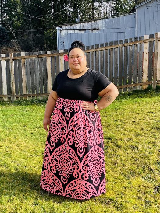 A reviewer in the empire-style dress with black on top and a pink and black floral-inspired pattern on the bottom