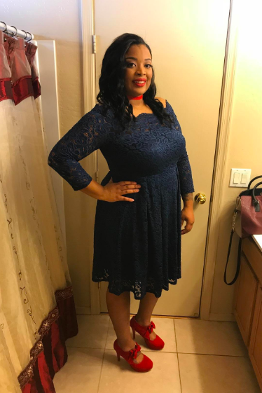A reviewer wearing a knee-length dress in deep navy blue.