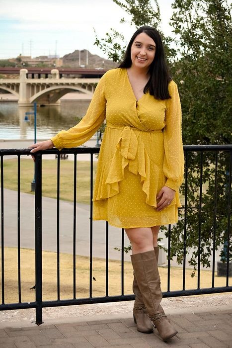 Reviewer wearing a ruffled yellow dot print wrap dress with a tie waist.
