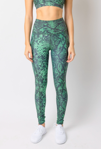 A model showcases green snake skin print leggings and white sneakers.
