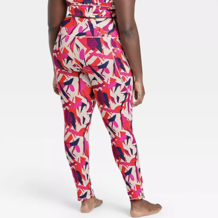 A model showcasing the back view of pink, red, cream, and navy blue geometric-patterned leggings