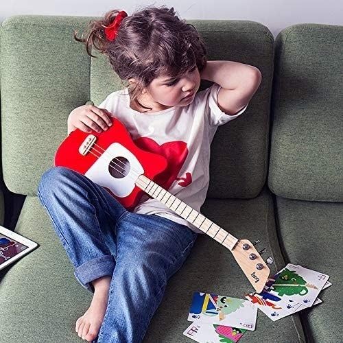 A child sitting on the couch, holding a red guitar.