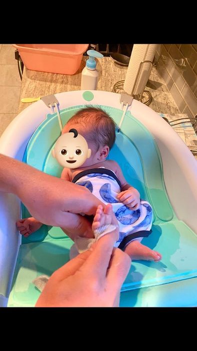 A baby happily splashing in the bathtub, enjoying a cozy bath time.