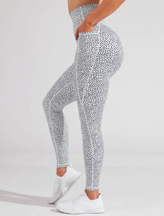 A model is showcasing white leggings adorned with black speckled dots.