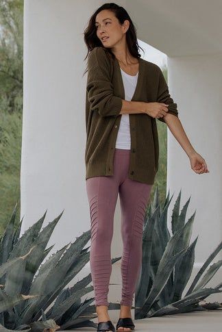 A model showcasing mauve ridged leggings styled with a cardigan outdoors, surrounded by plants